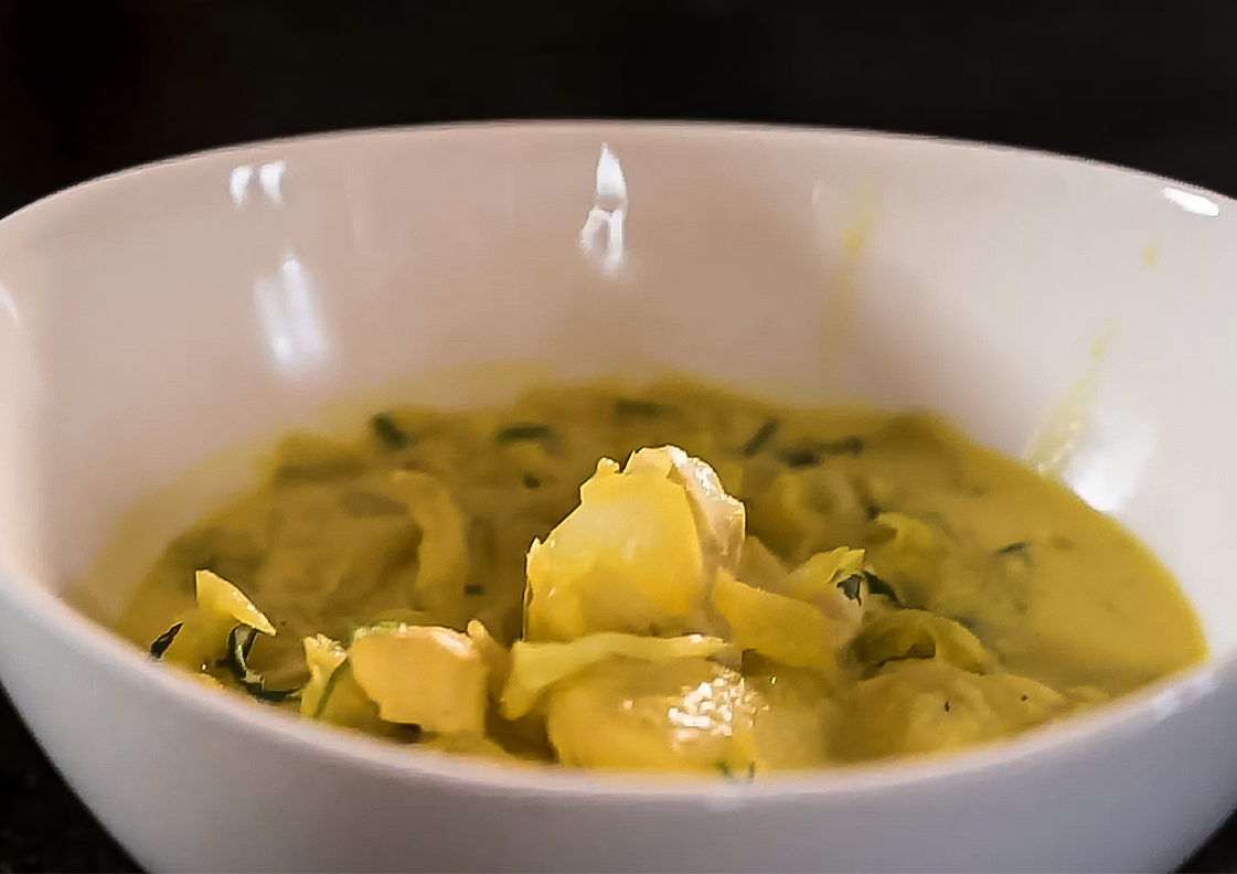 Krämig gul fisksoppa med saffran, hälleflundra och grönsaker serverad i en vit skål